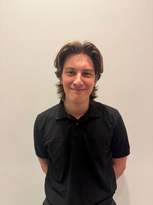 Photo of Aidan standing in front of white wall